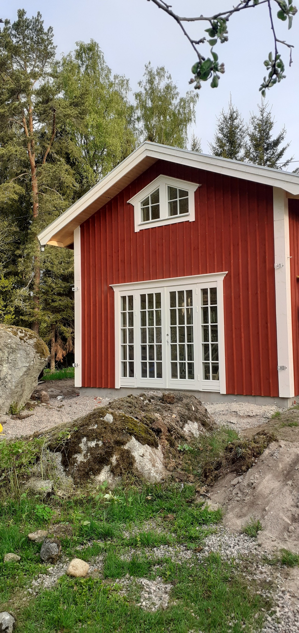 Vita spröjsade pardörrar och halvrunt gavelfönster på litet rött hus i Stöpen, monterade av Urhem Bygg & Snickeri